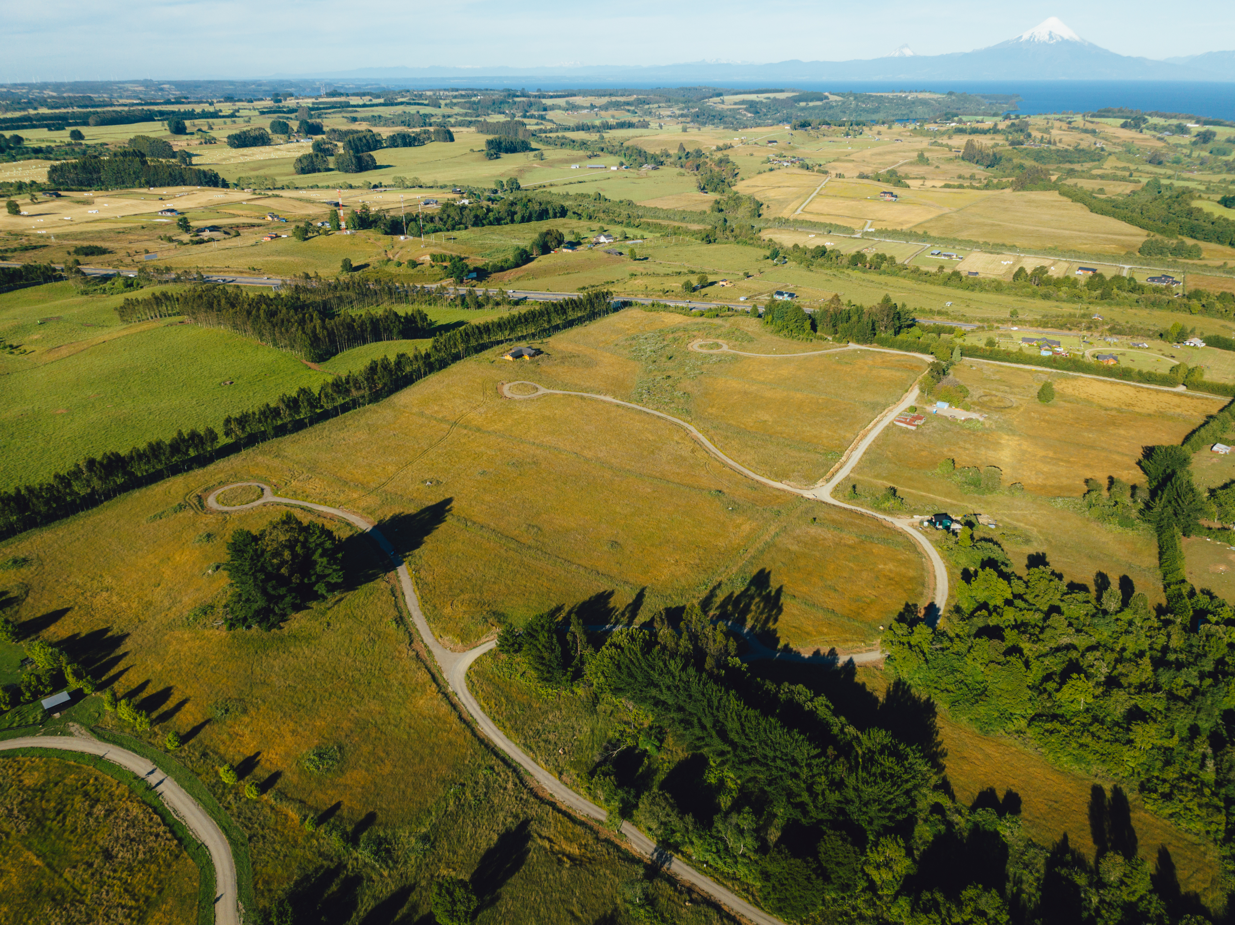 Vista aérea de parcelación con lago y volcán — lectura territorial en la cuenca